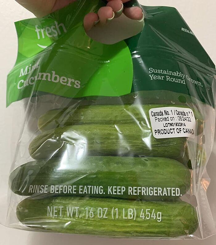 Hand holding a bag of Amazon Fresh mini cucumbers showcasing affordable staples cheaper than big box stores.