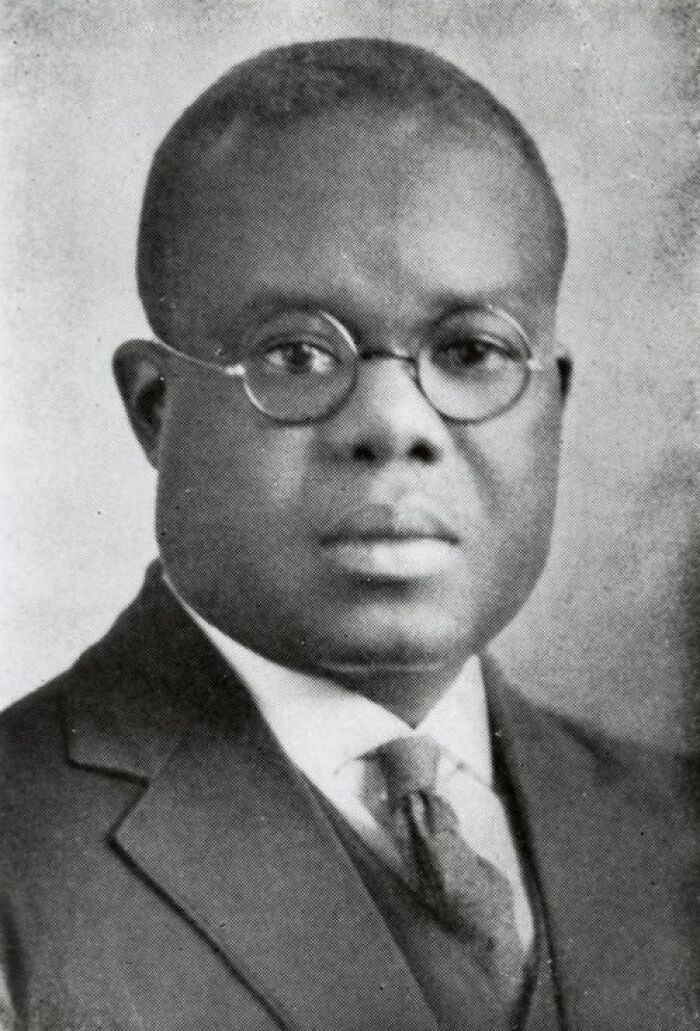 Portrait of a man in glasses and suit, representing a crucial moment in Harlem Renaissance history.