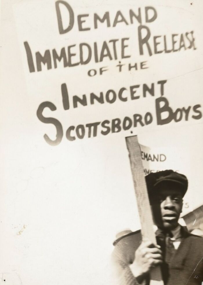 Protester holding a sign demanding justice for the Scottsboro Boys, a crucial moment in Harlem Renaissance history.