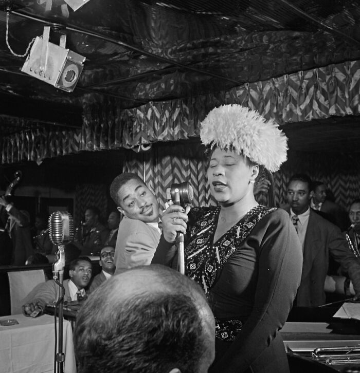Famous jazz singer performing during Harlem Renaissance with band and audience in an intimate club setting.