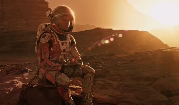 Astronaut in a space suit resting on rocky terrain during sunset in one of the new millennium's greatest films.