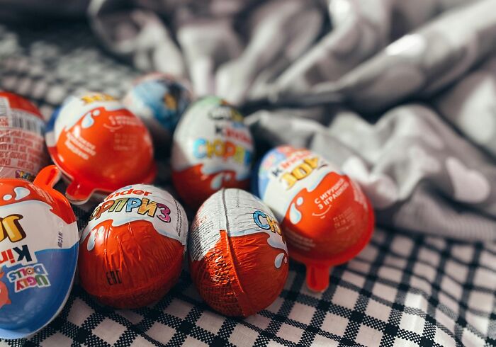 Kinder surprise eggs wrapped in colorful foil displayed on a checkered cloth highlighting banned foods in the USA.