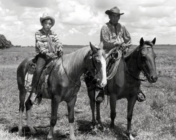 Two cowboys on horseback in a vintage black and white photograph capturing the old West and cowboy culture.
