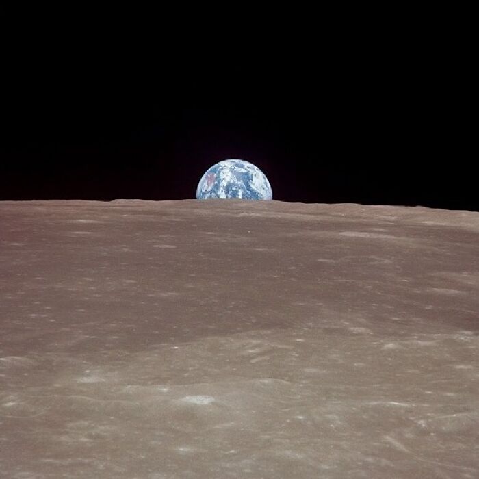 Earth rising above the lunar surface captured in an iconic Apollo mission photo showing the vast moon landscape.