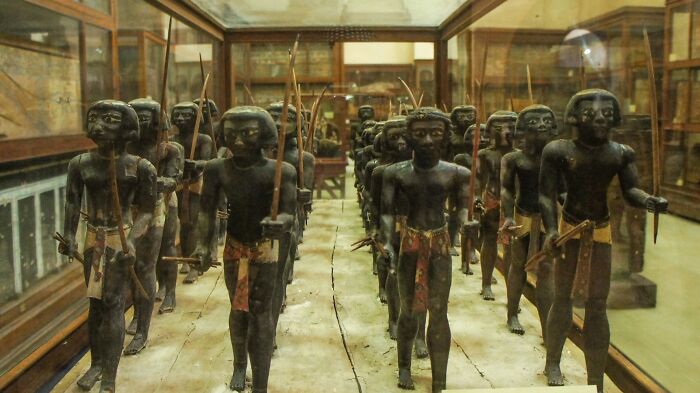 Wooden warrior statues displayed in a museum representing African American military history and heritage.