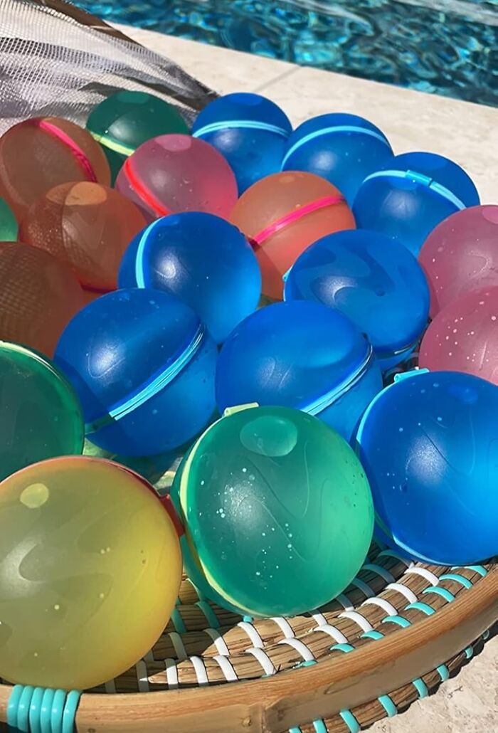 Colorful water balloons on a tray by the pool, perfect for summer annoyances and ways to fight back with fun activities.
