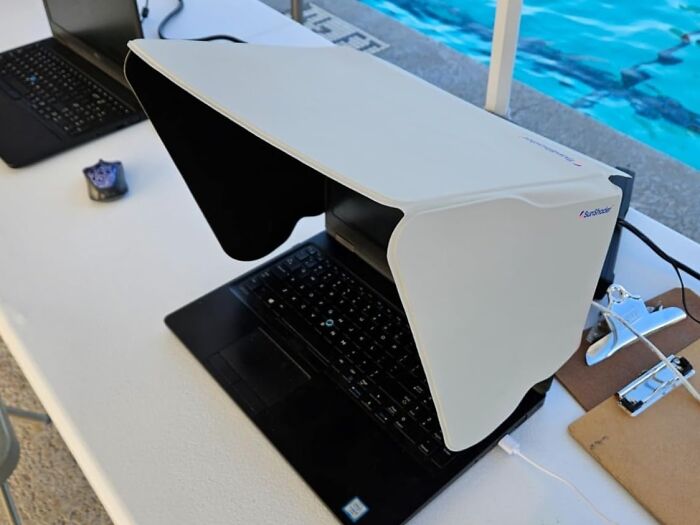 Laptop with sunshade protector by a pool, demonstrating a practical solution to stop summer annoyances and stay cool outdoors.