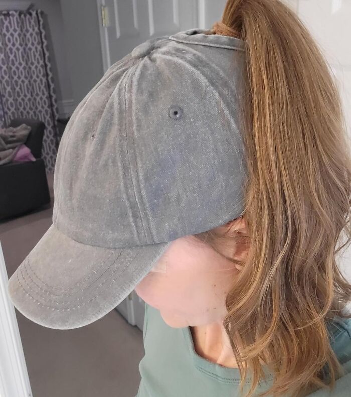 Woman wearing a gray ponytail baseball cap indoors, demonstrating a summer annoyance solution to fight back.