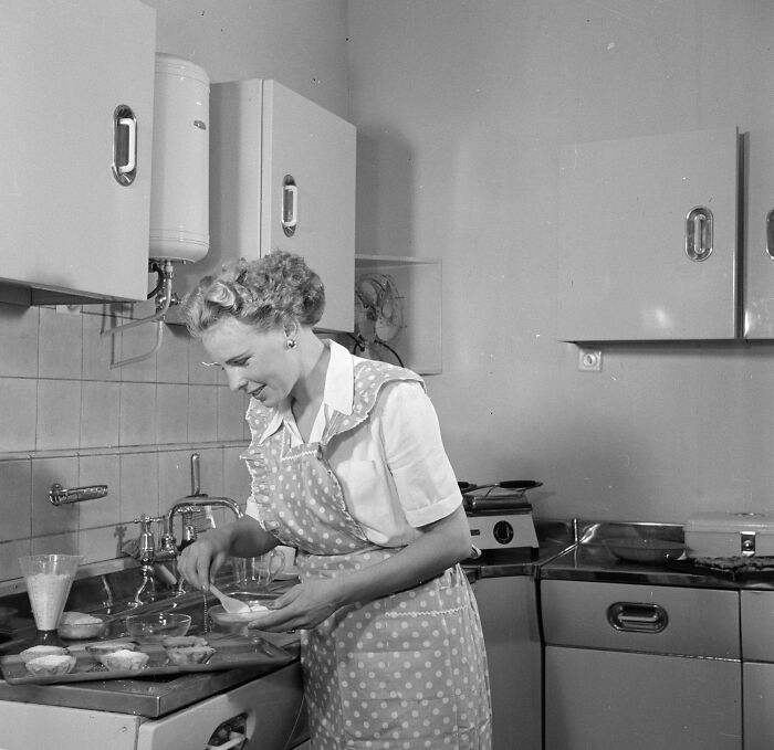 1940s housewife in a polka dot apron preparing food in a retro kitchen, capturing iconic housewife moments of the era.
