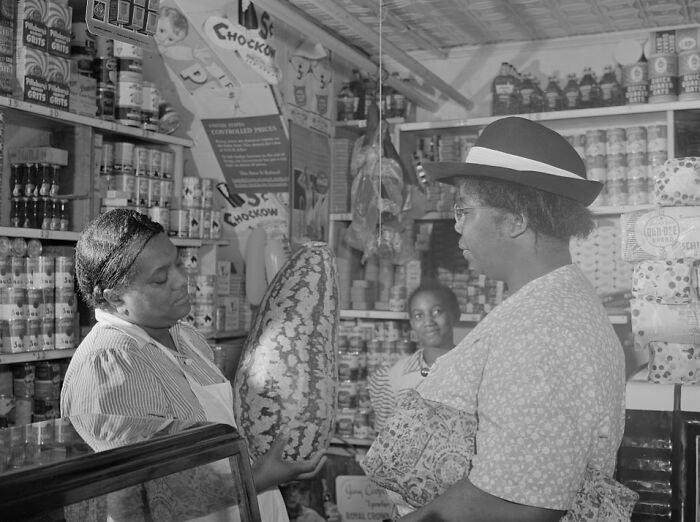 1940s housewives shopping and interacting in a grocery store filled with canned goods and household items.