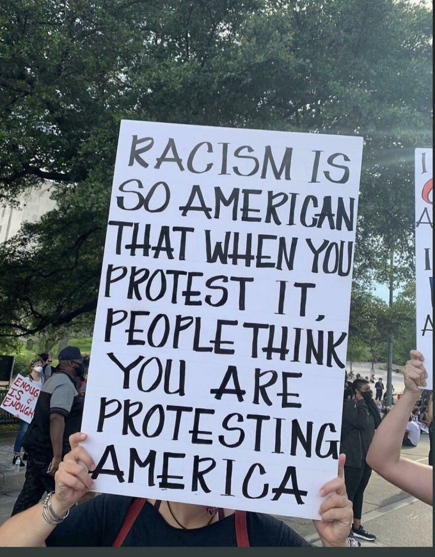 Handwritten protest sign with perfect handwriting example stating a message about racism and America at a public demonstration.