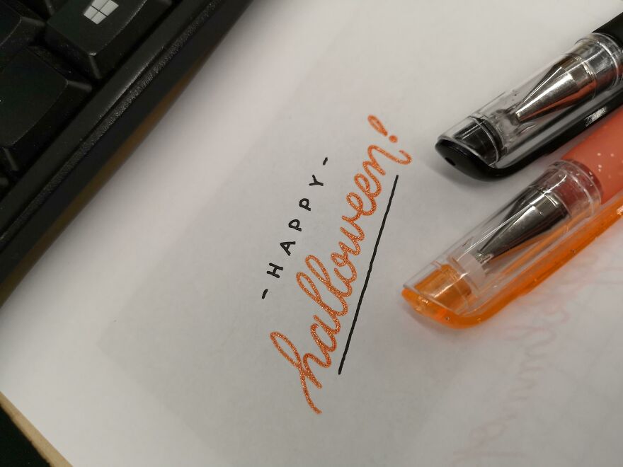 Close-up of perfect handwriting example featuring "Happy Halloween" written neatly with black and orange pens.