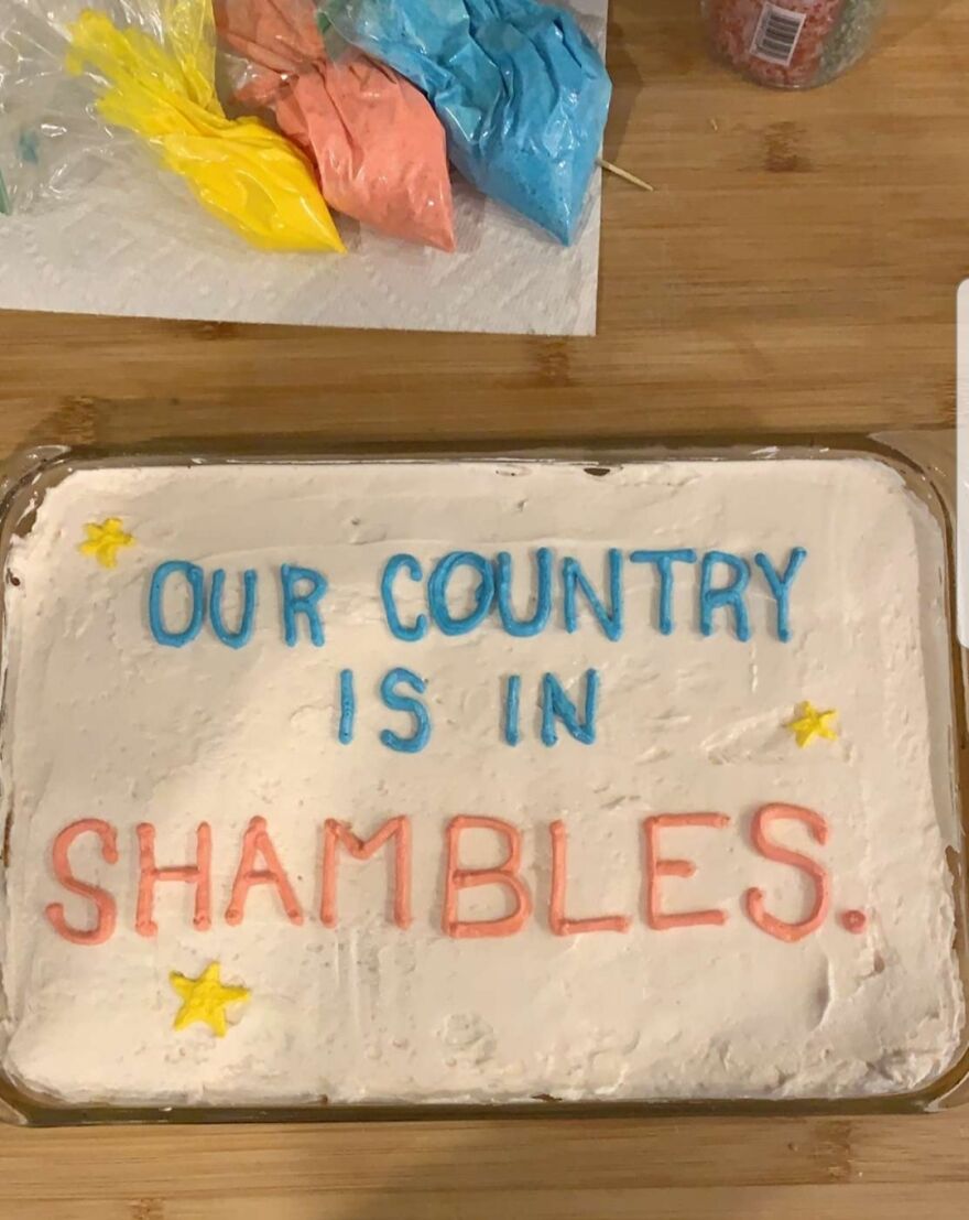 Cake with perfect handwriting decoration saying Our country is in shambles in blue and red frosting with star accents.