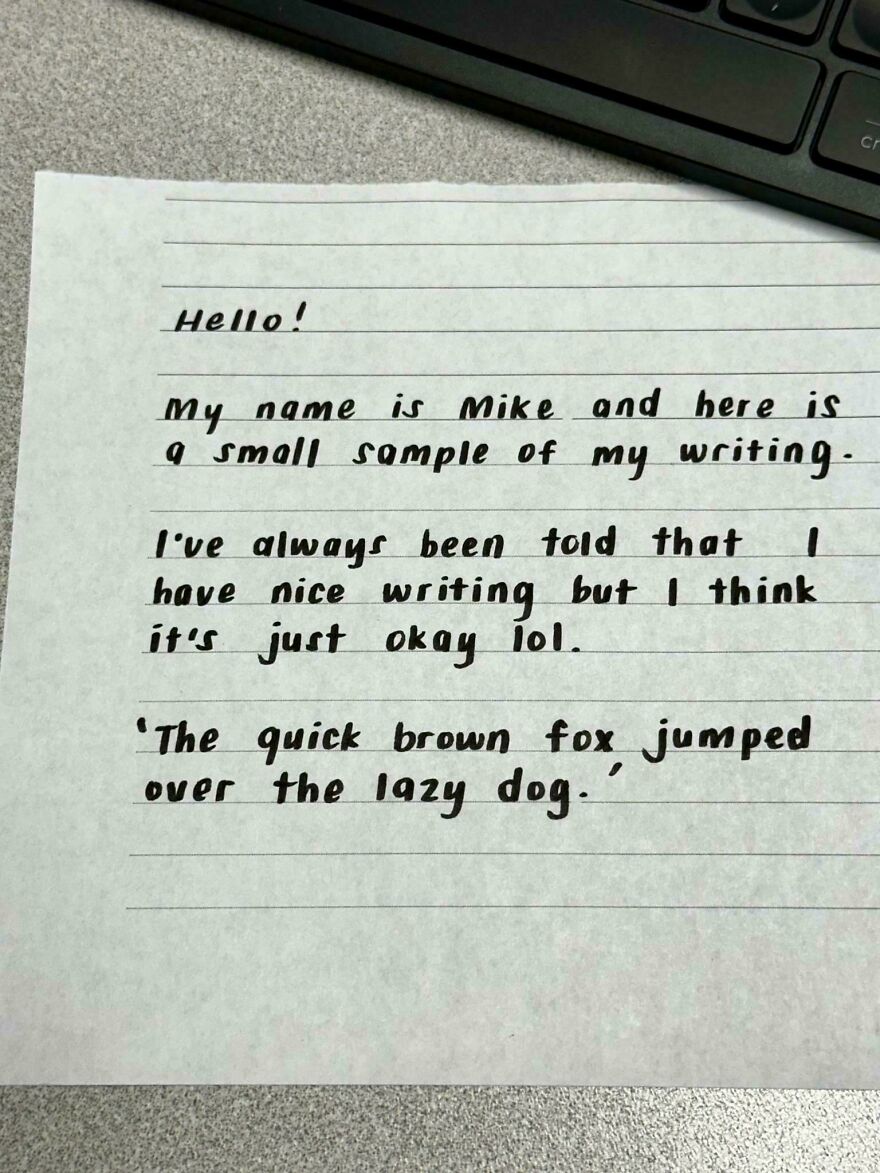 Handwriting example on lined paper showing neat, clear, and perfect handwriting near a keyboard.