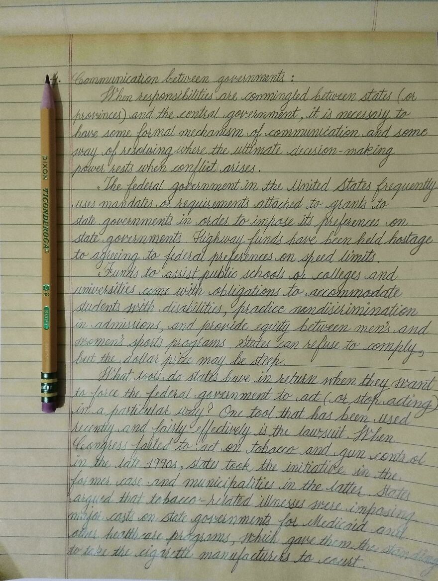 Perfect handwriting example of neat cursive writing on lined paper with a pencil placed on the left side