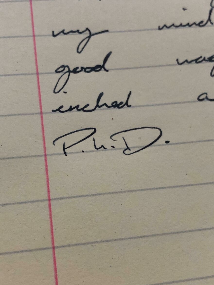 Close-up of a lined notebook page showing perfect handwriting examples with neat cursive and a clear signature.