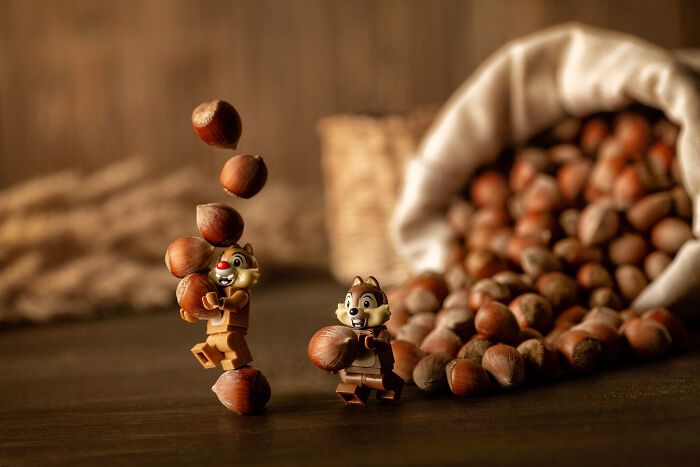 Two LEGO figures holding and juggling hazelnuts in front of a spilled sack of hazelnuts in a cinematic scene.