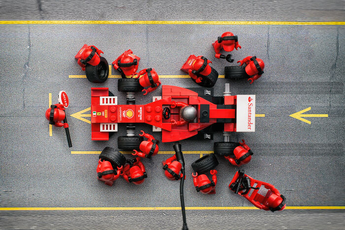 LEGO figures performing a detailed pit stop on a red LEGO race car, showcasing Hollywood-level LEGO scenes by a skilled photographer.