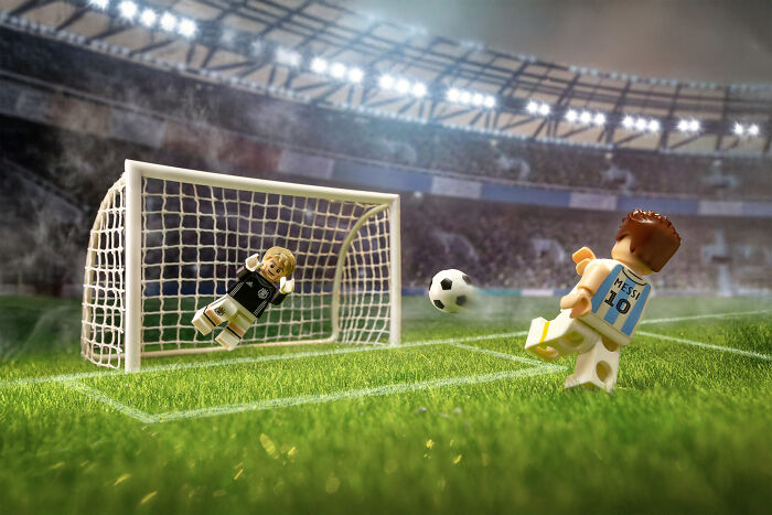 LEGO soccer scene with a player kicking a ball towards the goal captured in a Hollywood-level photography style.