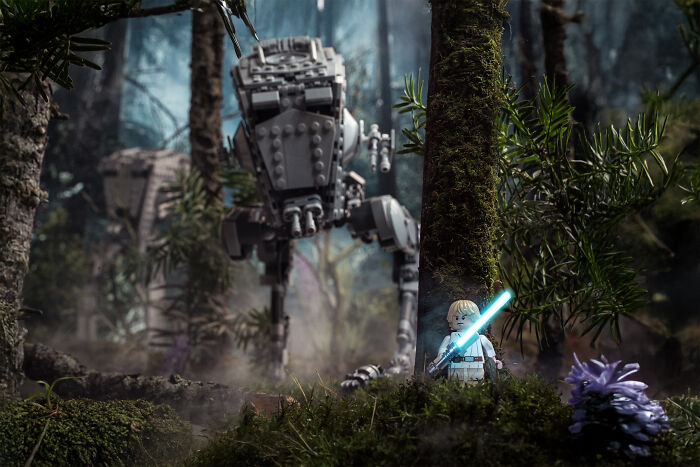 LEGO Star Wars scene recreated with a minifigure holding a lightsaber and a detailed AT-ST walker in a forest setting.