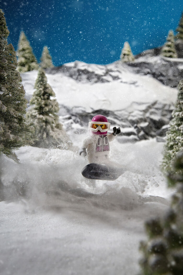 LEGO minifigure snowboarding in a detailed snowy mountain scene created by a photographer with Hollywood-level effects.