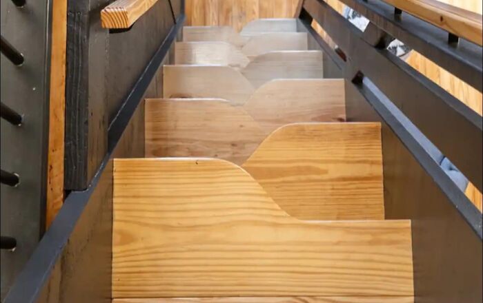 Unconventional death stairs with uneven wooden steps and minimal handrails leading to a loft, posing a safety risk.