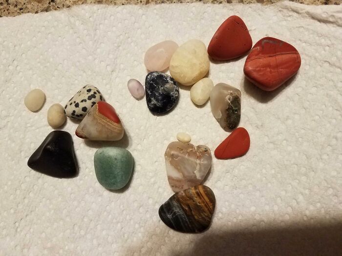 Assorted polished crafting stones arranged on a white textured cloth, showcasing popular crafting kit materials.