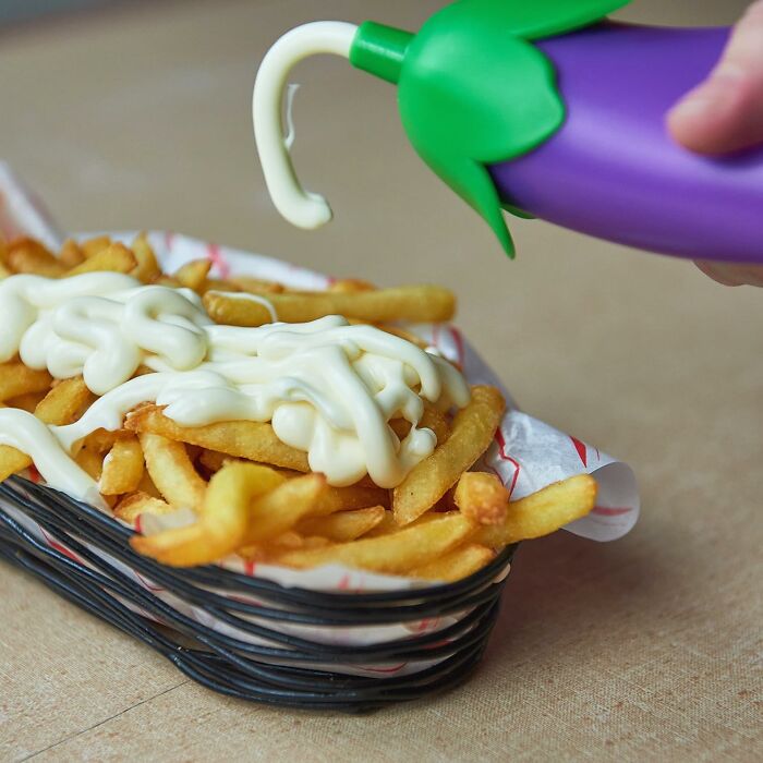 Close-up of best-selling kitchen item dispensing creamy sauce onto crispy French fries in a basket