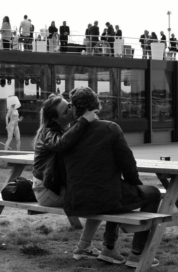 Couple sharing a tender moment on a bench in a street scene capturing the poetry of everyday life in black and white.