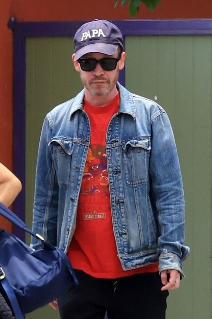 Man wearing sunglasses, a denim jacket, and a cap, looking unrecognizable as a beloved 90s child star at 44.