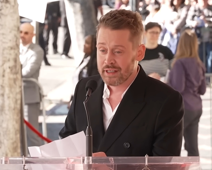 Beloved 90s child star at 44 speaking at an outdoor event, wearing a black blazer and white shirt. Beloved 90s child star at 44 speaking at an outdoor event, wearing a black blazer and white shirt.
