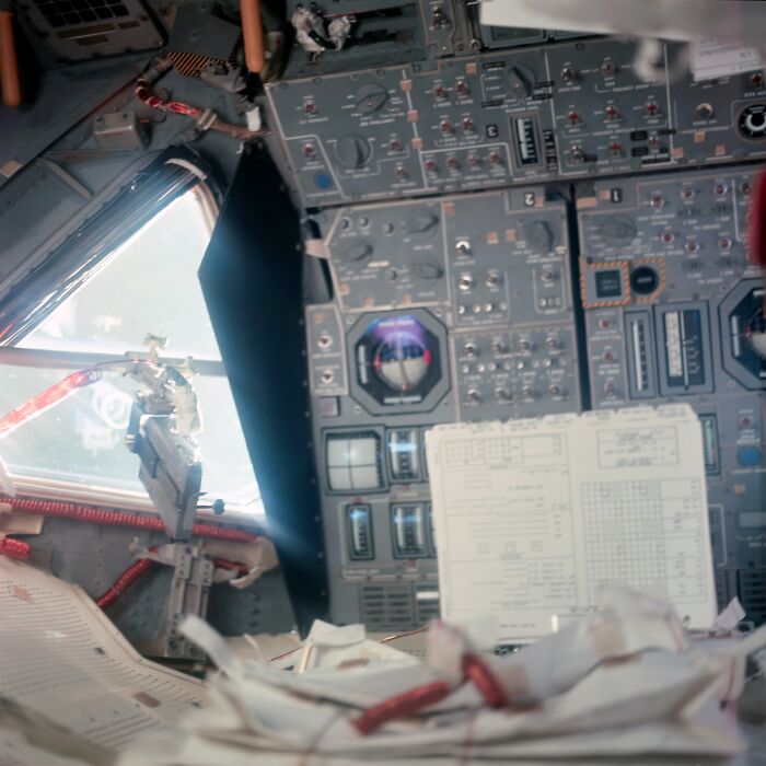 Apollo mission cockpit showing detailed control panels and documents inside the spacecraft during spaceflight.