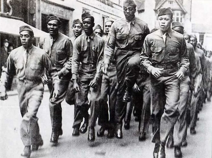 African American soldiers in uniform marching down a street showcasing military history and unity.