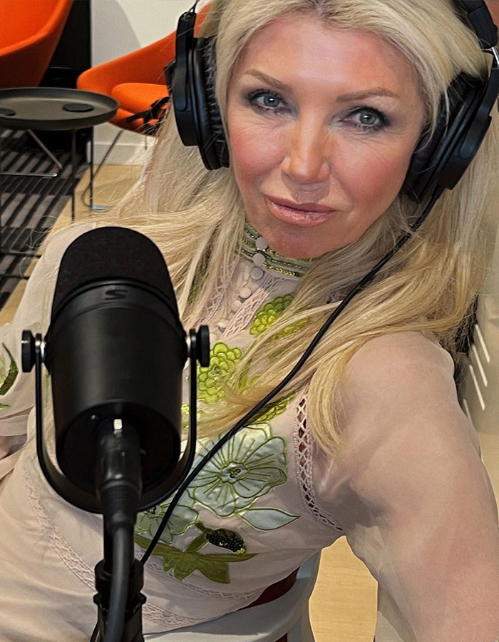 Woman wearing headphones speaking into a microphone in a recording studio, related to anti-vax mom claims and cancer.