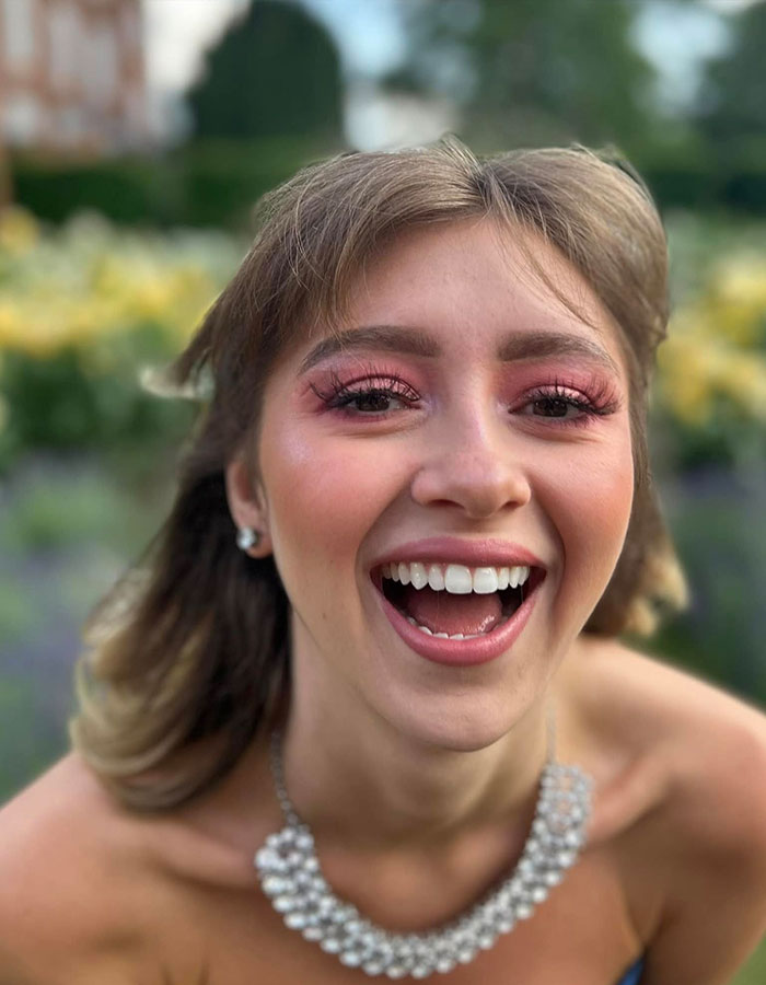 Young woman smiling outdoors, representing anti-vax mom of Cambridge 23-year-old graduate who passed away from cancer.