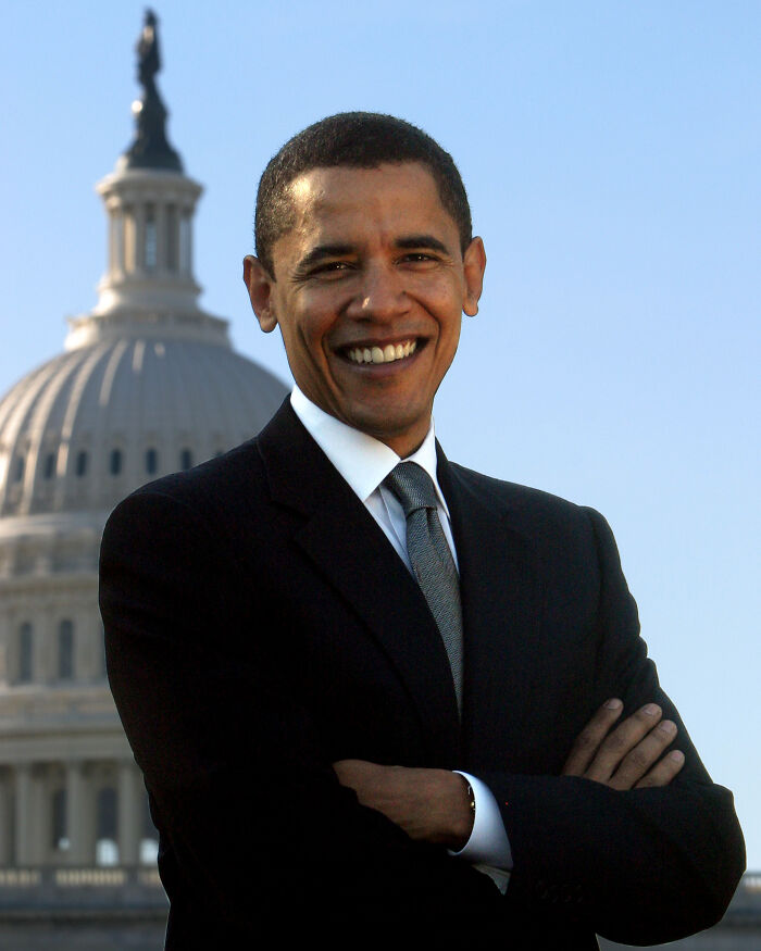 Smiling man in a suit standing in front of a government building, symbolizing late bloomers who became millionaires.
