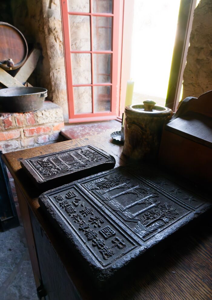 Antique printing blocks with historical engravings on a wooden table in a rustic room with natural light.