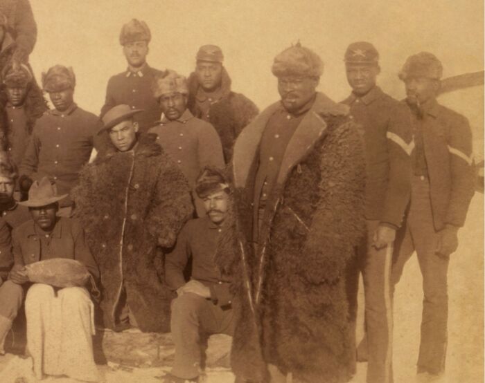 Group of African American soldiers in historical military uniforms and fur coats, representing African American military history.