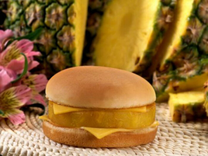 Pineapple cheesecake sandwich with cheese slices and fresh pineapple pieces in the background, history picture.