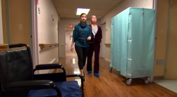 Woman walking with assistant in hospital corridor 16 years after face transplant from chimpanzee attack Woman walking with assistant in hospital corridor 16 years after face transplant from chimpanzee attack