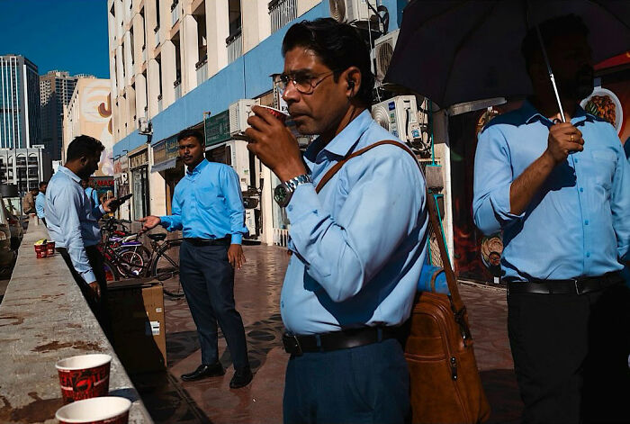 Men in blue shirts captured in candid street moments full of emotion on a sunny urban street by a traveling photographer.