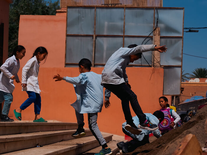 Children playing energetically on steps in a candid street moment captured by a photographer full of emotion.