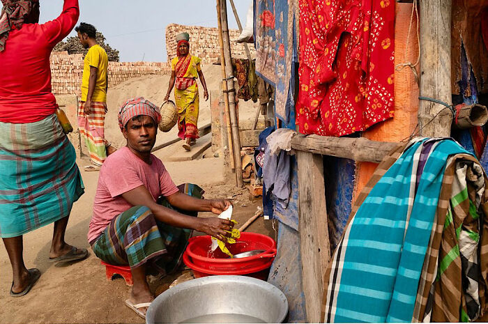 Man washing clothes on the street, capturing candid street moments full of emotion in a vibrant village setting.