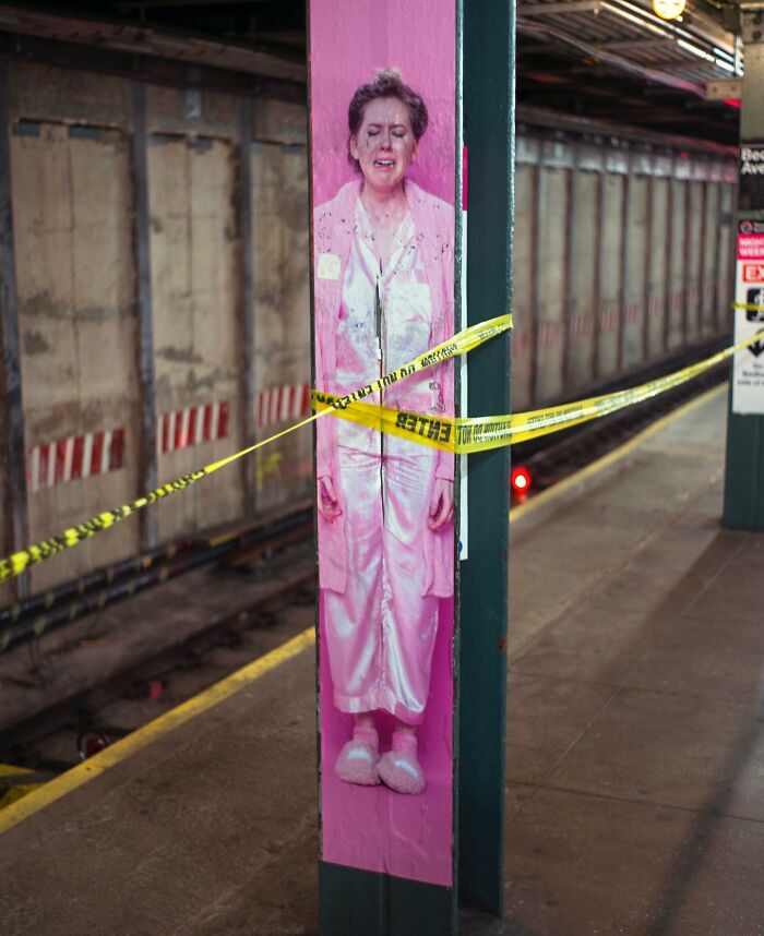Street photography capturing a pink figure alignment with yellow caution tape in a subway station, showcasing city life coincidences.