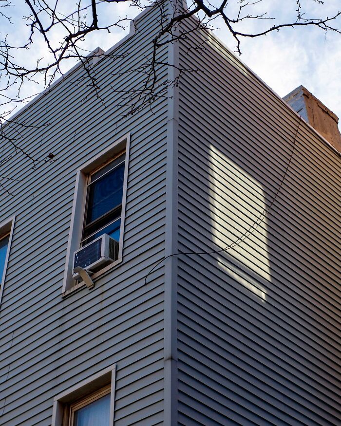 Corner of a city building with an air conditioner and shadow coincidence creating a magical street photography moment