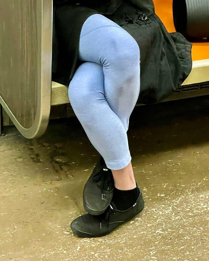 Legs crossed wearing light blue leggings and black shoes, captured in a street photographer's magical city life coincidence.