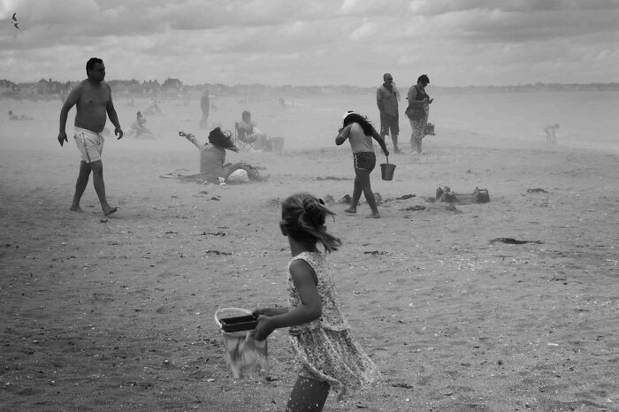 Black and white cinematic photo of people on a windy beach capturing everyday life moments by Adriana Ferrarese.