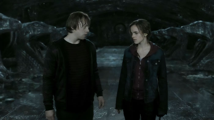 Emma Watson and Rupert Grint in a dark, cave-like setting from a Harry Potter film scene. Emma Watson and Rupert Grint in a dark, cave-like setting from a Harry Potter film scene.