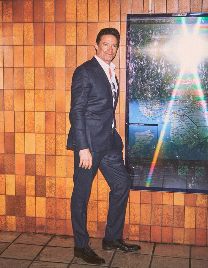 Hugh Jackman in a dark suit standing near a subway map, reflecting light, amid divorce setback rumors. Hugh Jackman in a dark suit standing near a subway map, reflecting light, amid divorce setback rumors.