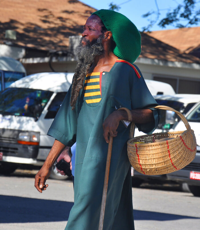 Man with a long beard and green hat holding a basket and cane outdoors, symbolizing fascinating theories about the afterlife.